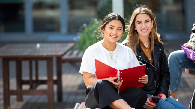 Two NCI students smiling and sitting on NCI campus